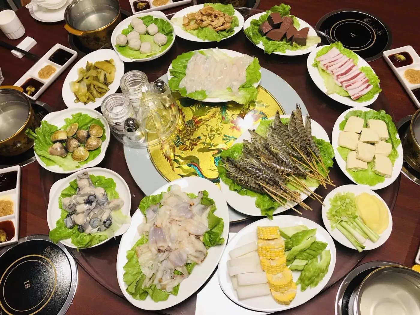 一桌潮汕菜:圆桌、转盘、各色生料分盘上桌。这是今日常见的席面,旧式八仙桌一方两客的座次不在此图中。图源:本站图库。