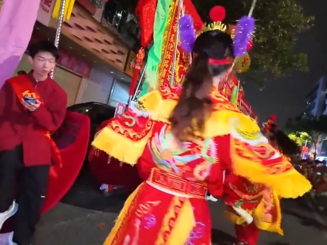一名队员头戴花冠,红绿戏服,双手上举