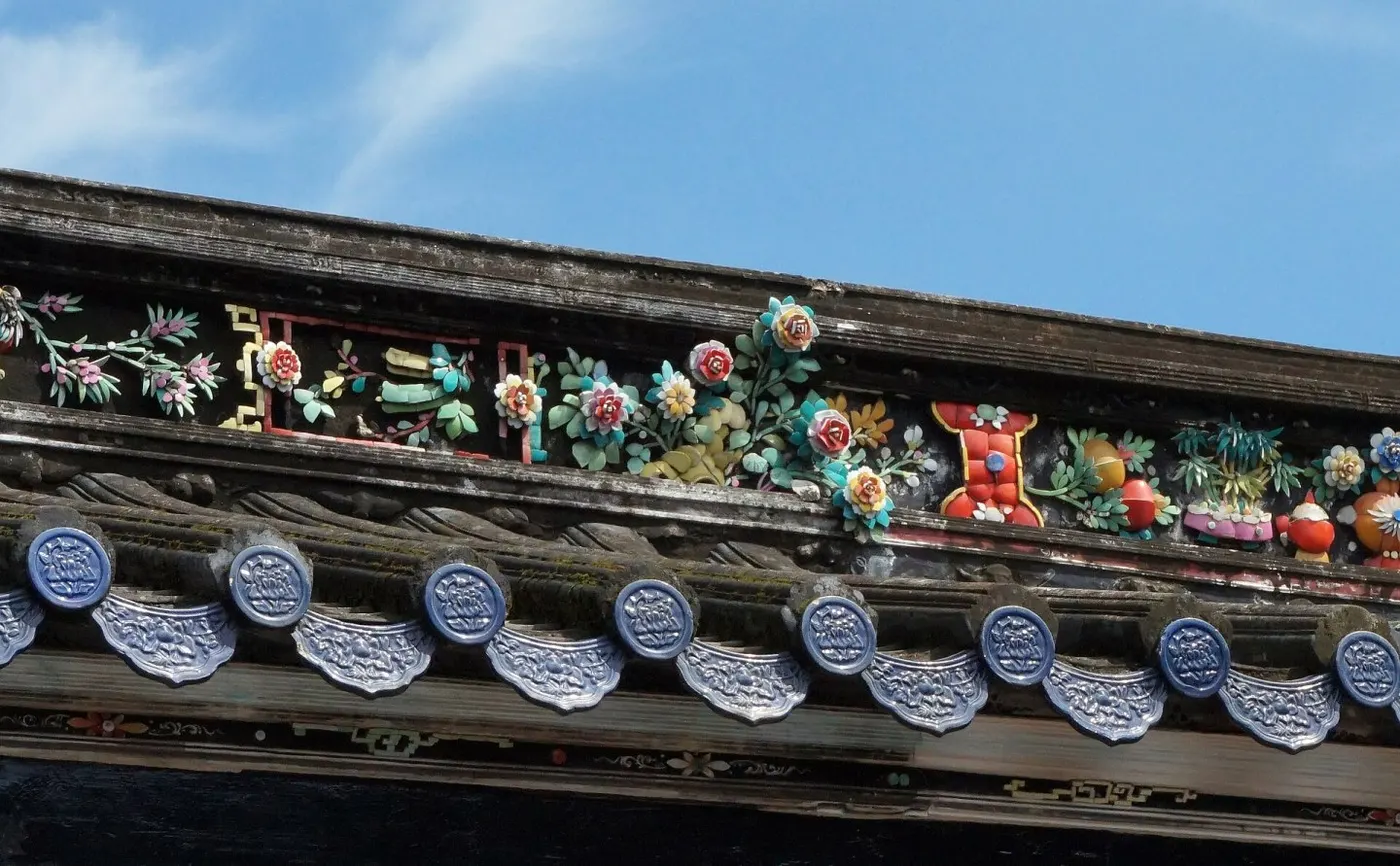 屋脊嵌瓷:花鸟、器物、博古,全由剪碎的彩瓷片嵌成;下方是蓝釉瓦当与滴水。三猎 摄,CC BY-SA 4.0,Wikimedia Commons。