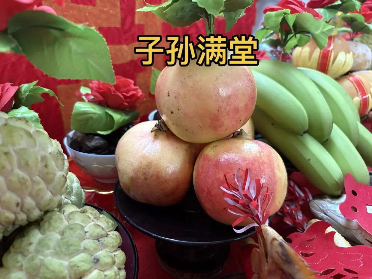 拜神桌上的五果:石榴、香蕉、释迦,果身贴红纸剪花。图源:抖音 @火山🌋,2025 年 10 月 17 日。
