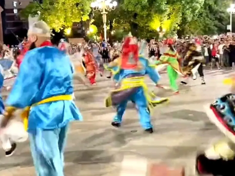 夜里街面,彩衣队员列队行进,两边站着人
