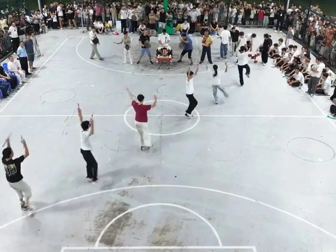 籃球場上幾名隊員把雙槌舉過頭頂,圍欄外站滿看的人