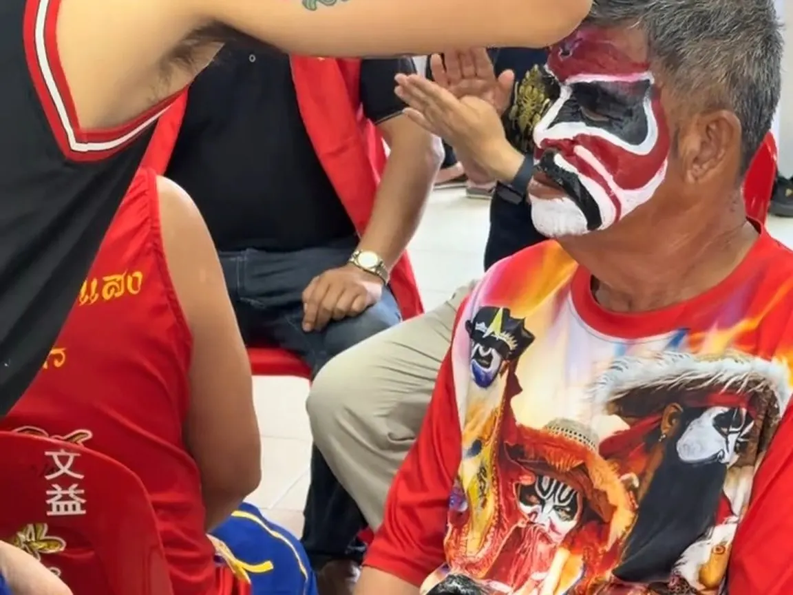 画好脸的人坐在红塑料椅上等上场,身上的 T 恤也印着脸谱