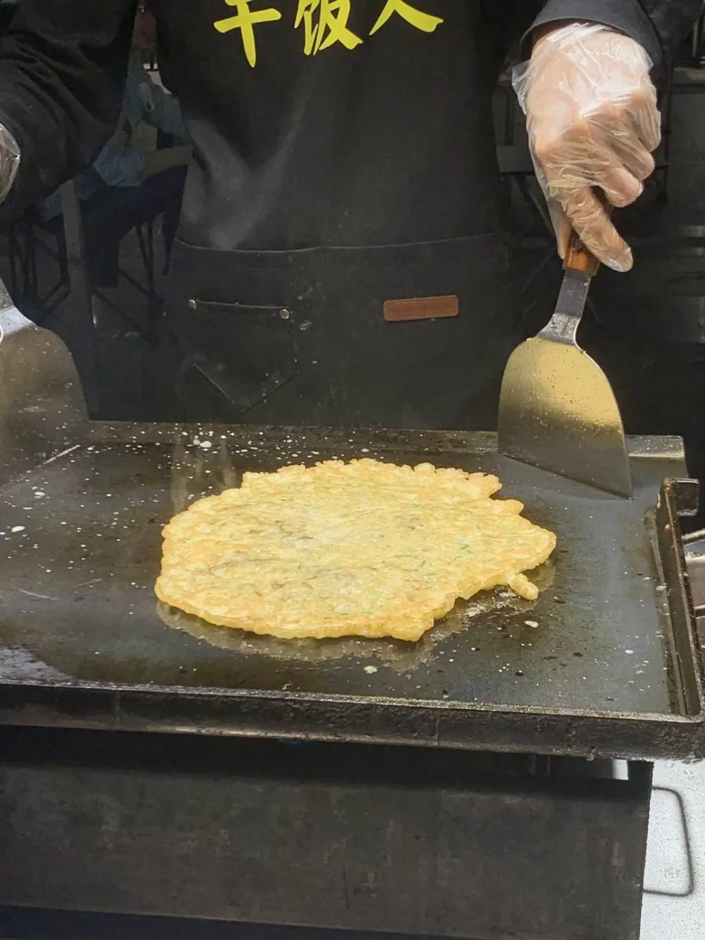 平底锅上摊开的蚝烙,正在两面翻煎