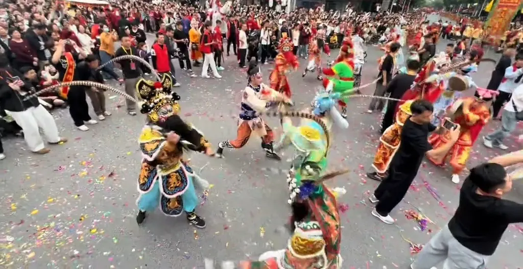街心两名队员腾身对击，长雉尾相交，地上铺一层彩色纸屑