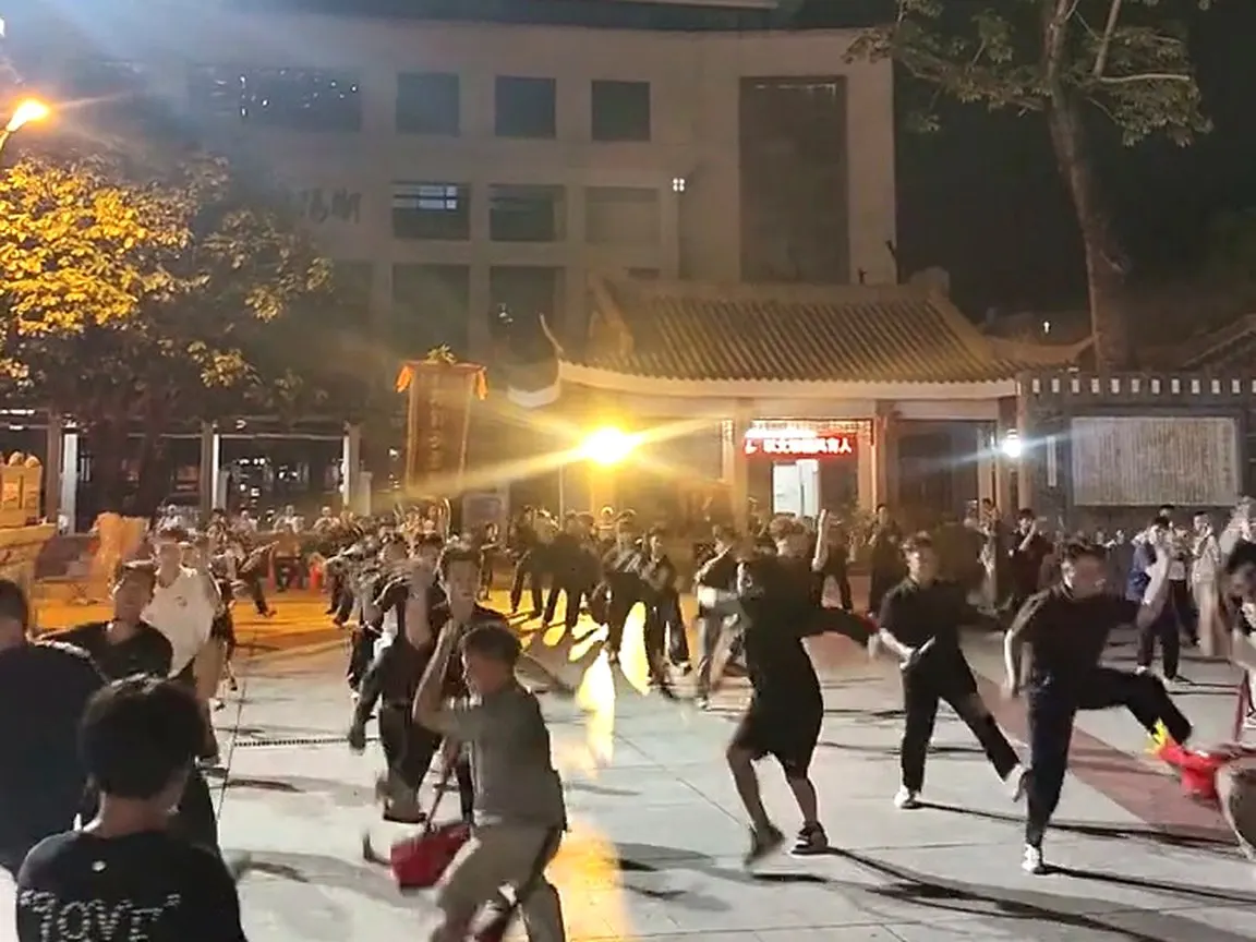 夜里广场，几十名未换戏服的队员在练槌，路灯拉出长影