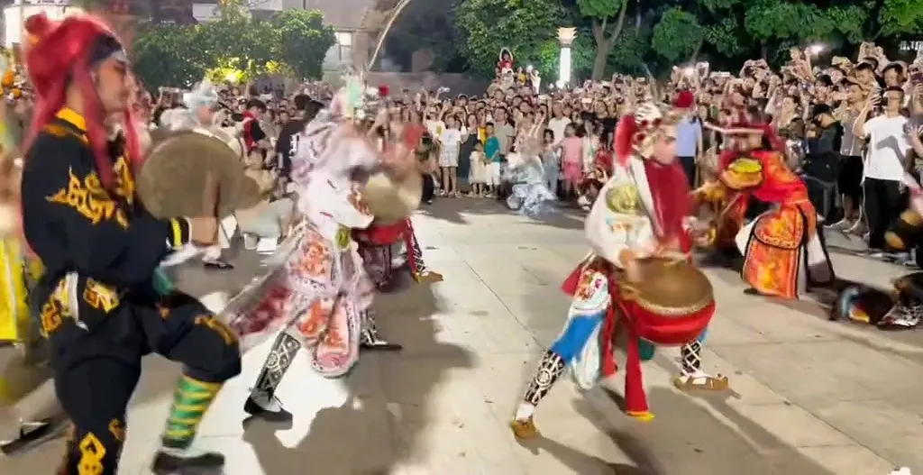 广场上三名队员,一人执大钹、两人各执小鼓