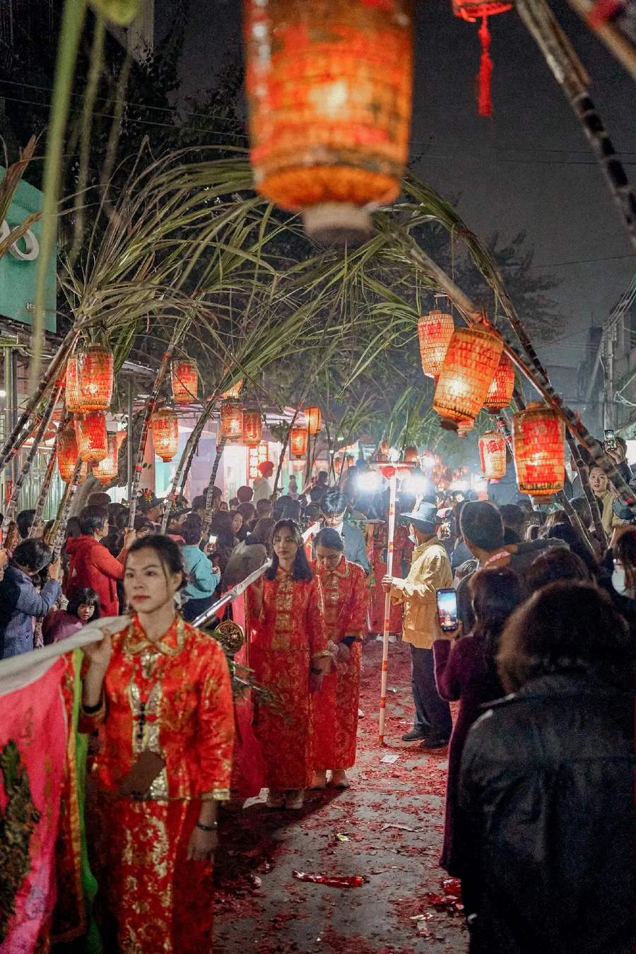 队伍沿蔗巷前行，灯在头顶