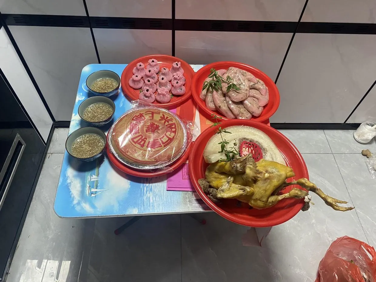 出花园的供桌:红盘里一只全鸡、一方猪肉、几色粿与米饭,另摆三碗甜汤。图源:抖音 @一只味精,2023 年 8 月 21 日。