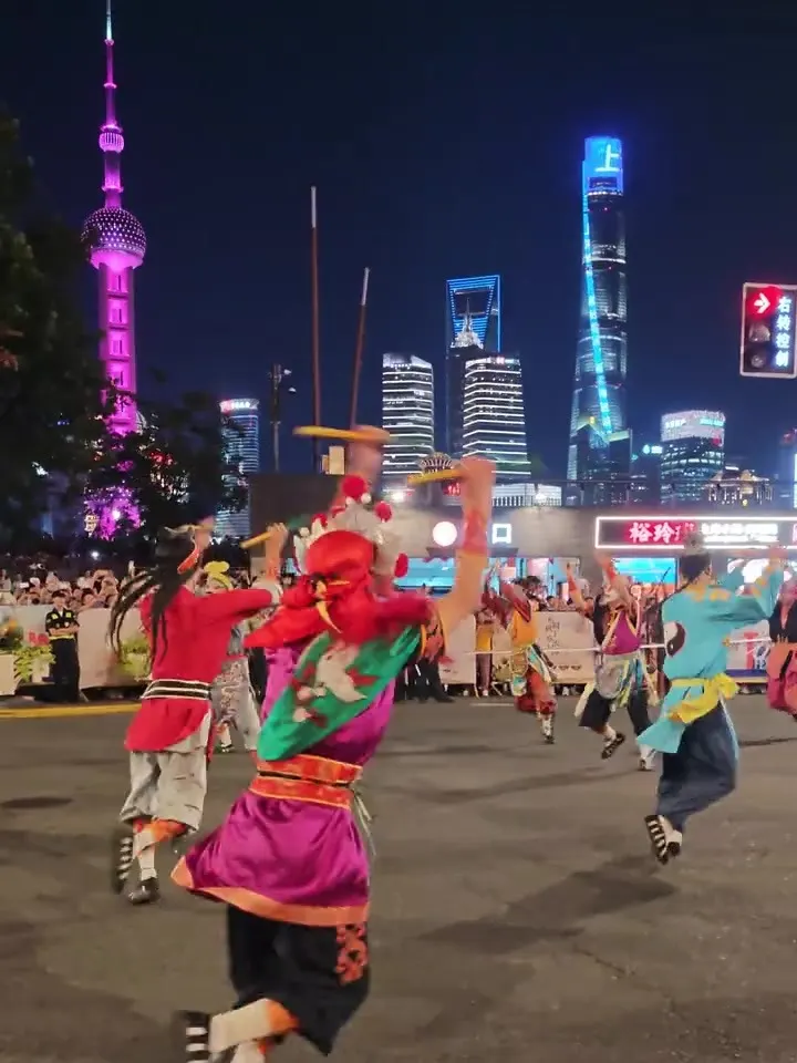 夜里外滩街上,一队勾脸队员腾身起舞