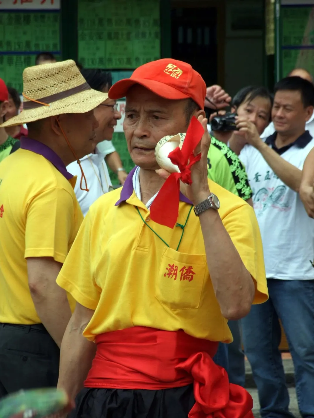 一名黄衫人把白色螺号贴在嘴边