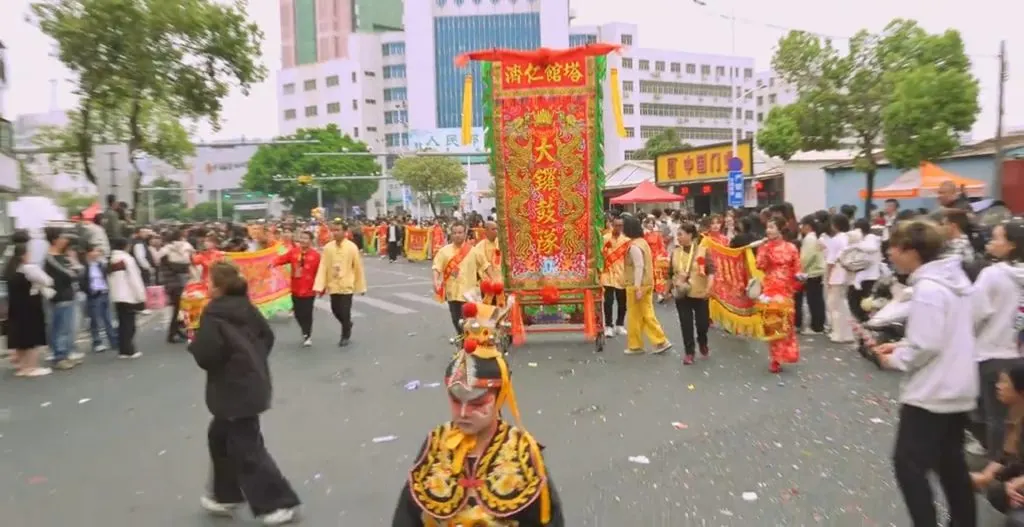 巡游队伍在街心走过,两侧是商铺与行人