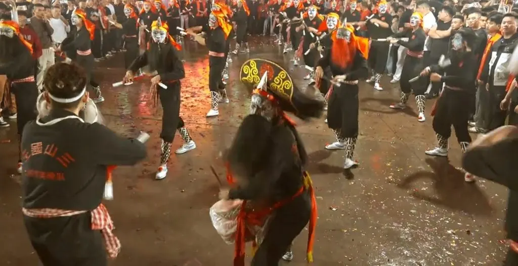 夜里满场队员举槌相向，近处一人背对镜头，衫上印「三山国王」