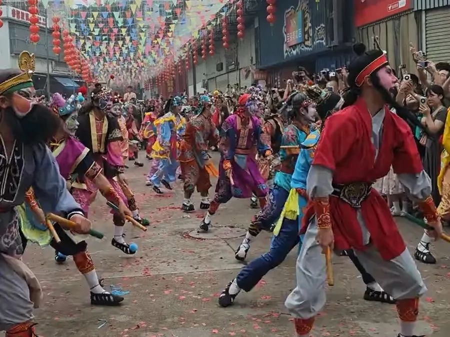 一名红脸队员走在队前,街心落满红纸